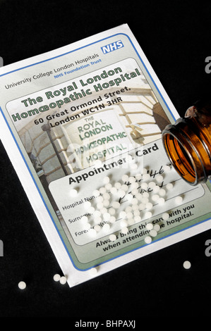 Die Royal London homöopathischen Krankenhaus Terminkarte mit verschüttete Pillen auf schwarzem Hintergrund Stockfoto