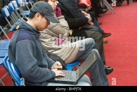 Ein chinesischer junge Mann sitzt mit einem Laptop während Chinese New Year Feierlichkeiten in Trafalgar Square in London UK Stockfoto