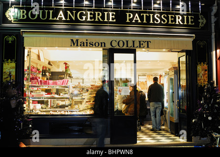 Paris, Frankreich, Leute, die Brot kaufen, Französisch Bäckerei Geschäft Frontfenster, Old French Storefront beleuchtet 'Maison Collet' Boulangerie Patisserie außen, Vintage, Small Shop france Licht Fenster Nacht, Business Storefront Stockfoto