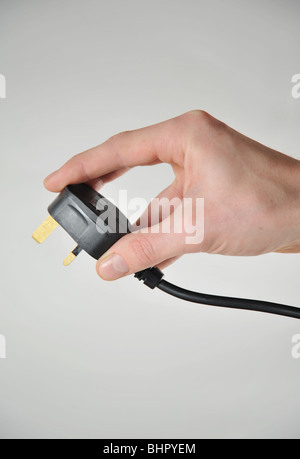UK-Stil 3-Pin-Stecker in eine Hand gehalten, als ob Sie in ein 240V Steckdose Strom-Steckdose stecken Stockfoto