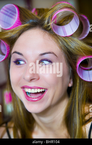 Frau mit Lockenwicklern im Haar lächelnd in Überraschung nach der Sitzung machen Stockfoto