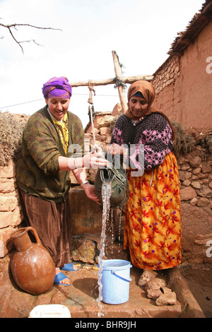 Berber Frauen sammeln das Wasser aus einem traditionellen Brunnen in einem Dorf im Hohen Atlas, Marokko, Nordafrika Stockfoto