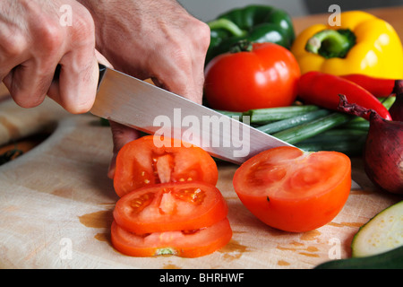 Nahaufnahme eines Mannes Hände schneiden rote Tomate Stockfoto