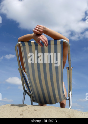 Frau im Liegestuhl am Strand Sonnenbaden Schuss gegen blauen Himmel Stockfoto