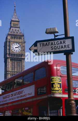 1970 das Londoner Parlament rote BUS SCHILD London Westminster 1970 Archiv historisches Bild traditionellen Blick auf Big Ben in den Häusern des Parlaments, mit traditionellen roten Doppeldeckerbus routemaster Bus mit Werbebanner und 1970 im alten Stil Straßenverkehr Zeichen zum Trafalgar Square im Vordergrund. Westminster London UK Stockfoto