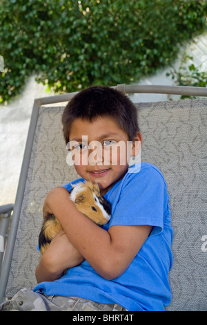 Portrait 8-9 Jahr alt Spanischer junge entspannt entspannend spielen mit seinem Meerschweinchen auf außen schwingen. United States cute HERR © Myrleen Pearson Stockfoto