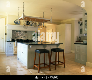 Leder und Holz Hocker am Frühstücks-Bar auf Insel Gerät in Bauernküche mit Kalkstein Bodenbelag Stockfoto