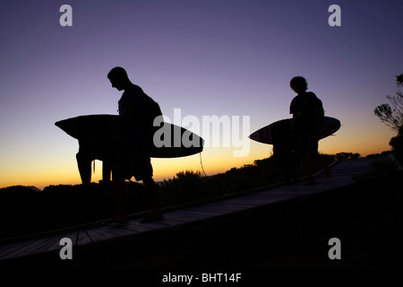 Surfer, die in Richtung zum Strand bei Sonnenaufgang Stockfoto