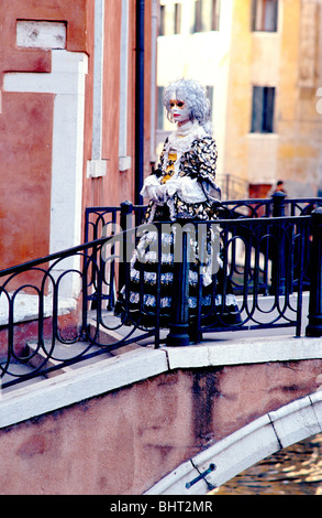 Dame im Kostüm überqueren eine kleine Brücke in Venedig während des Karnevals Stockfoto