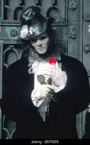 Schwarzen & weißes Kostüm, silberne Maske & rote Rose am Karneval von Venedig Stockfoto