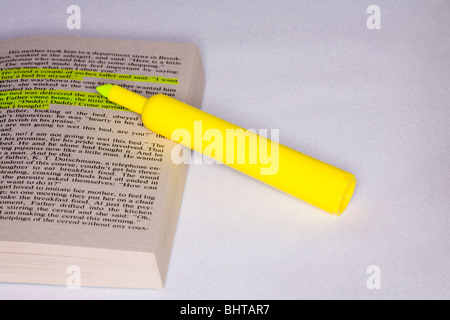 Gelber Textmarker mit Taschenbuch und hervorgehobenem Text Stockfoto