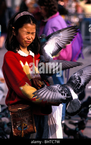 Erschrockenes orientalische Mädchen mit ihren Augen fest geschlossen, füttern von Tauben in Markusplatz entfernt, Venedig, Italien Stockfoto