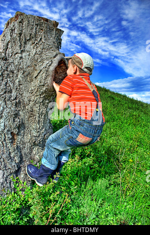 Kleinen Bauern auf einer Wiese sitzen auf einem Baumstamm Stockfoto