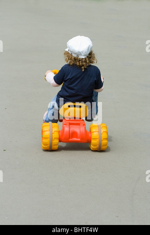 Kleiner Junge reitet ein Dreirad auf einem Bürgersteig Stockfoto