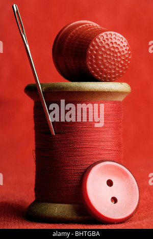 alle roten Nähen Artikel - Spool-Faden, Nadel, Fingerhut und eine Schaltfläche Stockfoto