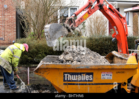 Minibagger bei der Arbeit Graben auf dem Bürgersteig, Gasleitung, UK zu ersetzen. Stockfoto
