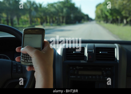 Frau nutzt PDA zu überprüfen und geben Sie SMS-Nachrichten während der Fahrt ihr Auto Stockfoto