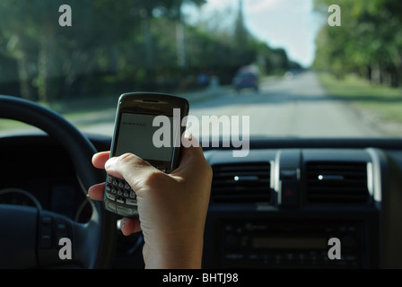 Frau nutzt PDA zu überprüfen und geben Sie SMS-Nachrichten während der Fahrt ihr Auto Stockfoto