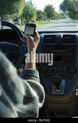 Frau nutzt PDA zu überprüfen und geben Sie SMS-Nachrichten während der Fahrt ihr Auto Stockfoto