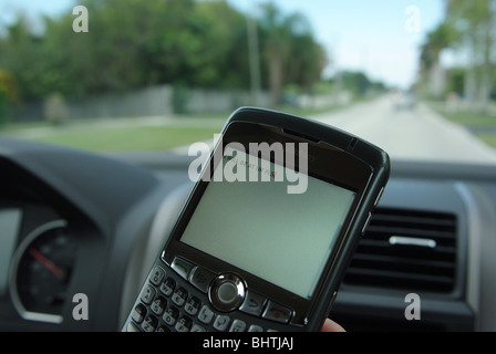 Frau nutzt PDA zu überprüfen und geben Sie SMS-Nachrichten während der Fahrt ihr Auto Stockfoto