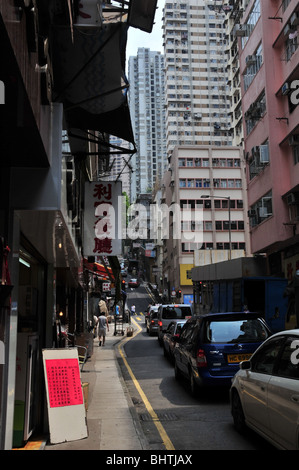 Autos, die Schlange an der Ampel in einer schmalen Seitenstraße zwischen Des Voeux Road West und Queens Road West, Hong Kong, China Stockfoto