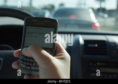 Frau nutzt PDA zu überprüfen und geben Sie SMS-Nachrichten während der Fahrt ihr Auto Stockfoto