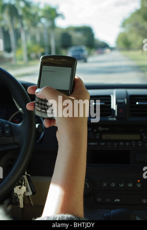 Frau nutzt PDA zu überprüfen und geben Sie SMS-Nachrichten während der Fahrt ihr Auto Stockfoto