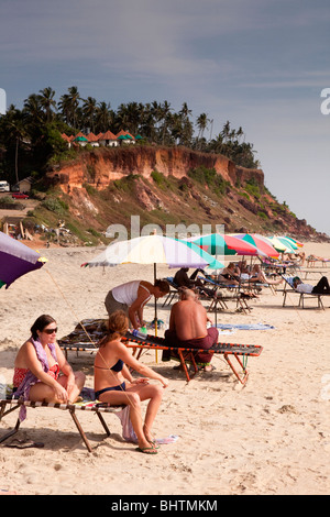 Indien, Kerala, Varkala Beach, Besucher aus dem Westen unter bunten Sonnenschirmen Sonnenbaden Stockfoto