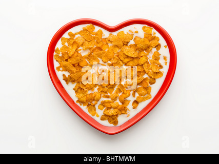 Studio shot der rote Herzförmige Schüssel Cornflakes und Milch auf einem weißen Hintergrund, von oben geschossen. Stockfoto