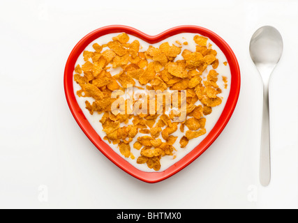 Studio shot der rote Herzförmige Schüssel Cornflakes und Milch auf einem weißen Hintergrund, von oben geschossen. Stockfoto