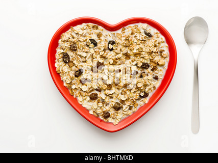 Studioaufnahme rote Herzförmige Schüssel Müsli und Milch auf einem weißen Hintergrund, von oben geschossen. Stockfoto