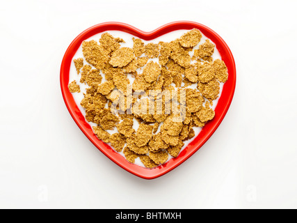 Studio shot der rote Herzförmige Schüssel von oben mit Kleie-Flocken und Milch auf weißem Hintergrund Stockfoto