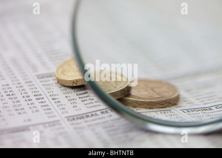 Makroaufnahme von 1- und 2-Pfund britische Münzen auf einer Zeitung Anzeige Aktien und Aktien Preise durch eine Lupe betrachtet. Stockfoto