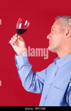 Mann ein Glas Rotwein für Klarheit und Qualität prüfen Stockfoto
