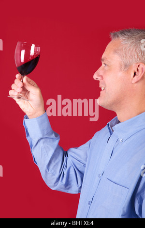 Mann ein Glas Rotwein für Klarheit und Qualität prüfen Stockfoto