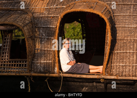 Indien, Kerala, Alappuzha, Chennamkary, westliche Besucher sitzen im Fenster der vorbeifahrenden Kettuvallam Hausboot Stockfoto