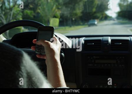 Frau nutzt PDA zu überprüfen und geben Sie SMS-Nachrichten während der Fahrt ihr Auto Stockfoto