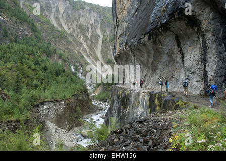 Wanderer zu Fuß auf schmalen Felsvorsprung in senkrechten Felswand über dem Fluss in der Nähe von Bhratang Dorf, Annapurna Circuit, Nepal Stockfoto