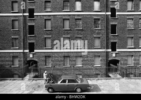 Viktorianische Mietshäuser, Peabody Housing Estate. Tower Hamlets Whitechapel East London UK 1970s Arbeiter arbeiten an seinem Auto vor seinem Wohnblock. 1975 HOMER SYKES Stockfoto