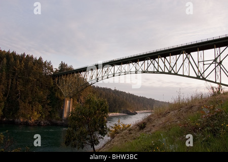 Diese Brücke erstreckt sich über einen Kanal des Wassers bei Sonnenuntergang. Am Deception Pass im US-Bundesstaat Washington mit Bergen und Wäldern. Stockfoto