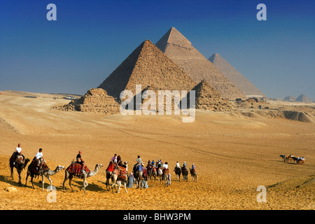 Touristen, Kamelreiten bei den Pyramiden von Gizeh, Kairo, Ägypten. Stockfoto