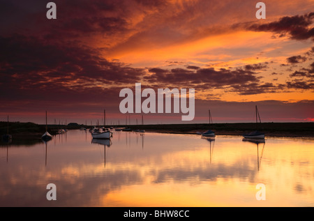 Roter Himmel über dem Hafen in Burnham Overy in Norfolk. Himmel und Boote zu reflektieren, in die Stille Wasser bei Flut Stockfoto