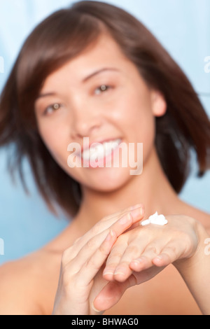 Eine schöne junge chinesische asiatische Frau Anwendung feuchtigkeitsspendende Handcreme, liegt der Fokus auf ihre Hände in den Vordergrund. Stockfoto