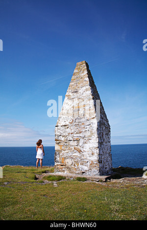 Stand Frau Blick auf das Meer neben der Küste Leuchtturm am Porthgain, entlang der Pembrokeshire Küste im Westen von Wales, UK Stockfoto