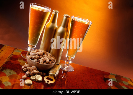 Goldene Bier, geröstete Erdnüsse, Öffner und Kappen Stockfoto