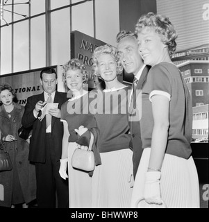 England Fußballer Billy Wright wird von seiner Freundin Joy Beverley Sisters begrüßt, als er am Londoner Flughafen, kommt nach Englands Beseitigung von der Weltmeisterschaft 1958 in Schweden. Hier wird er durch die anderen beiden Zwillingsschwestern Teddie und Babette verbunden. 23. Juni 1958. Stockfoto