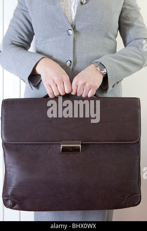 Frau mit schwerem Leder Businesstasche mit beiden Händen Stockfoto