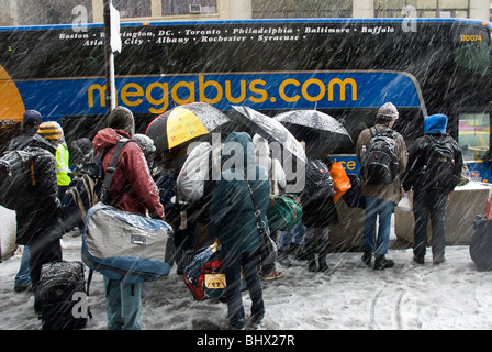 Reisende warten, um einen Megabus im Schnee in New York an Bord Stockfoto