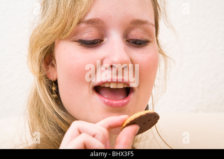 Junge Frau wird versucht, einen Cookie zu essen Stockfoto