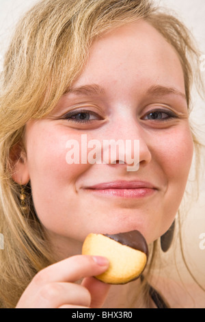 Junge Frau, die einen Cookie essen Stockfoto